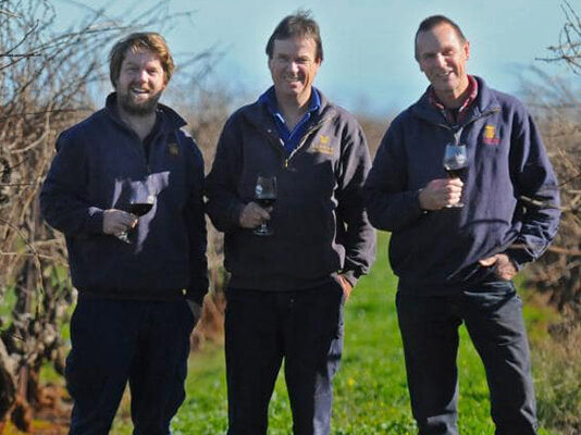 Dan, Bruce and Mal standing in the Redman Vineyard with glasses of wine